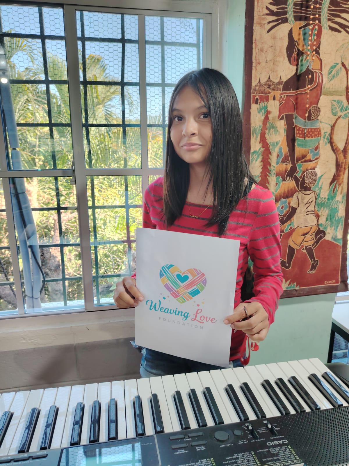 Boy holding a Weaving Love Foundation page beside a keyboard